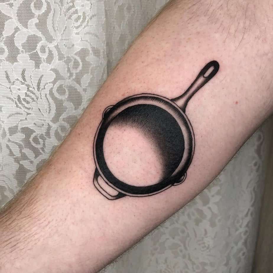 14. A tattoo of a cast iron pan on the inside of the arm