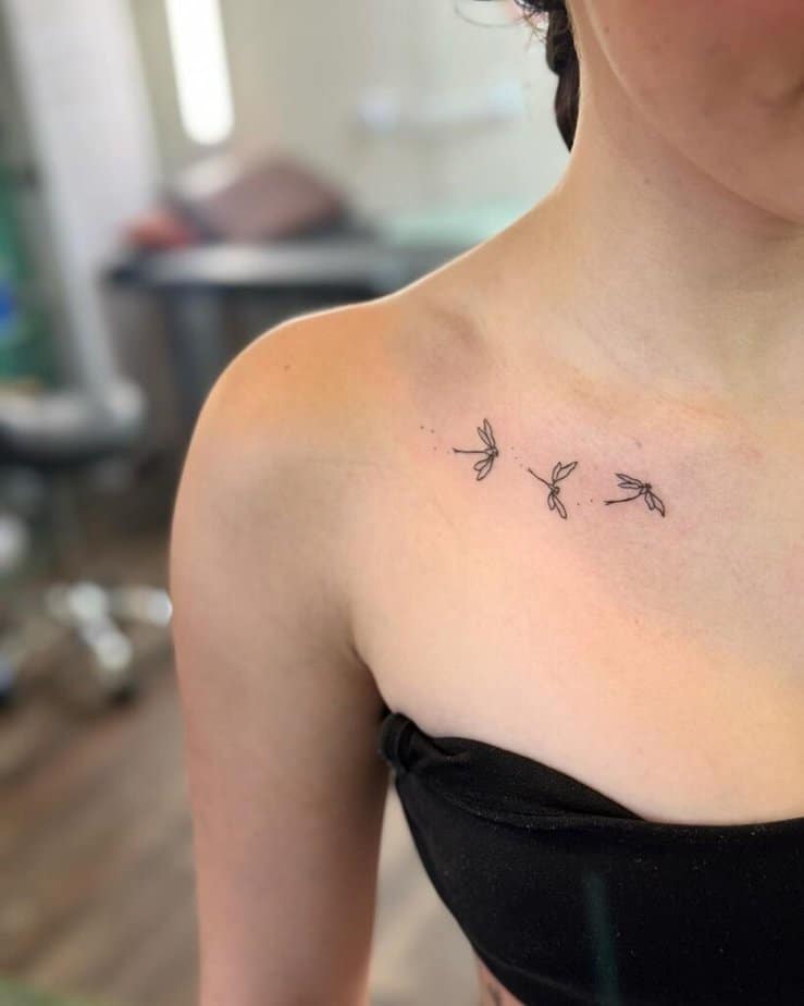 4. A tattoo of three fine-line dragonflies on the collarbone