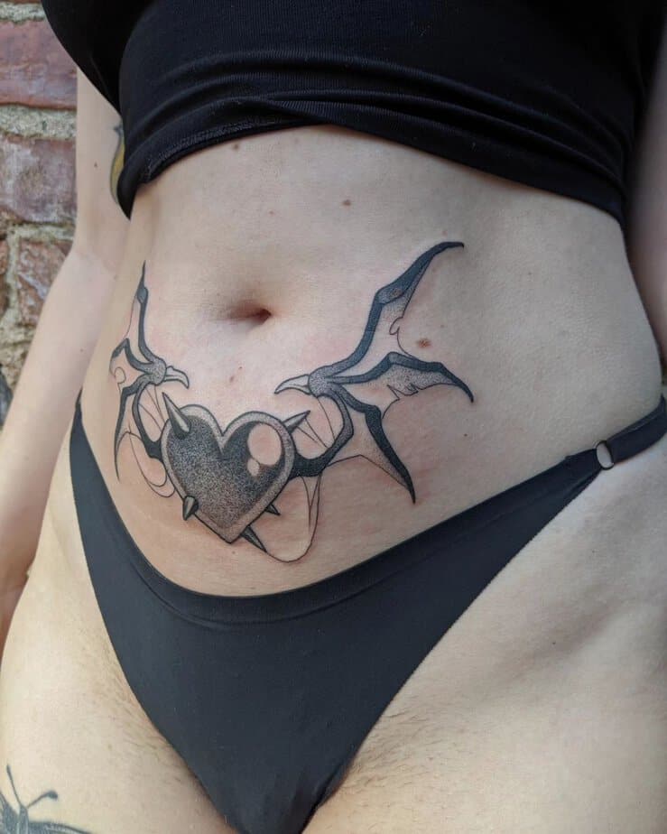 17. A tummy tuck tattoo of a heart with horns and demon wings