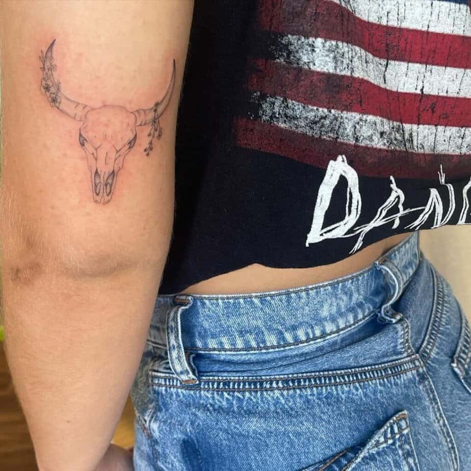 20. A tattoo of a cow skull with flowers 