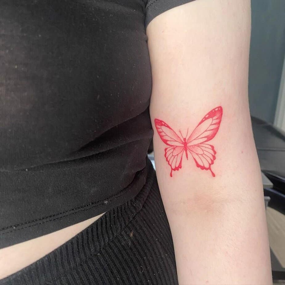 19. A soft and subtle red butterfly tattoo