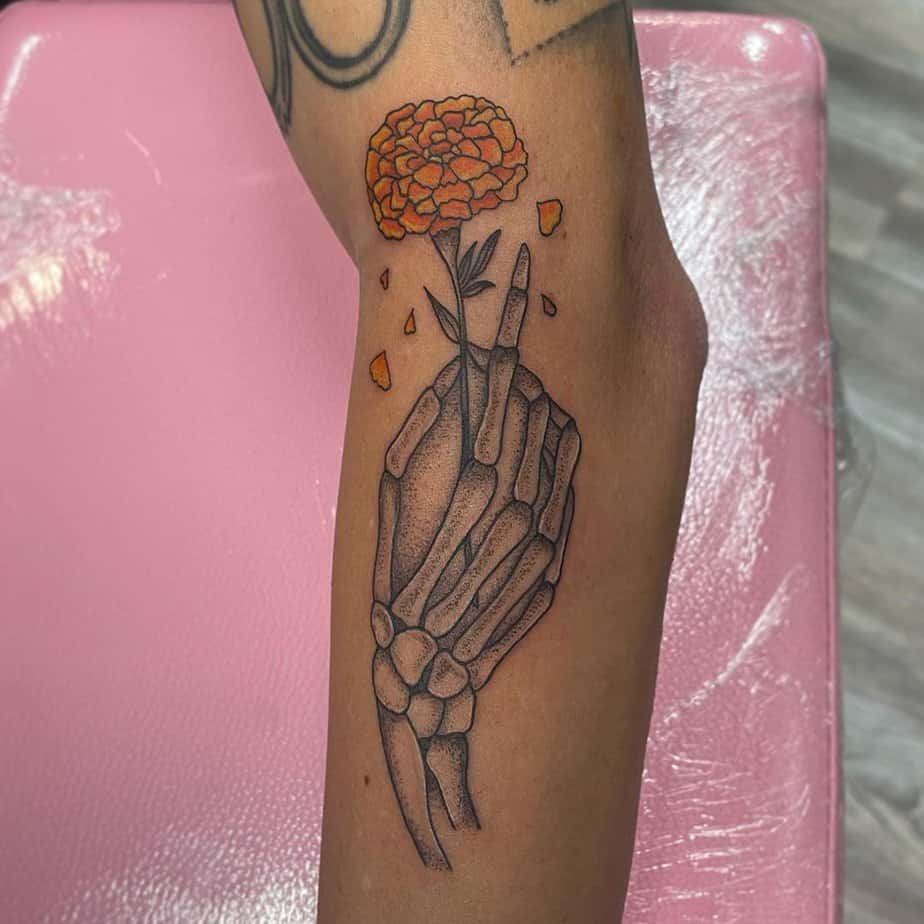 Skeleton hand with marigold leg tattoo